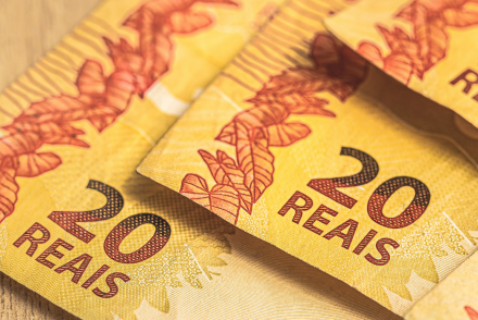 Três notas de vinte reais em fundo amarelado. Como ganhar dinheiro em 2022